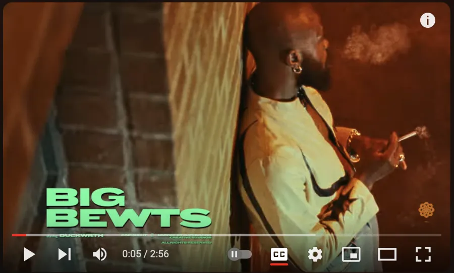 Thumbnail for the youTube video showing Duckwrth smoking smoking while leaning on a brick wall.