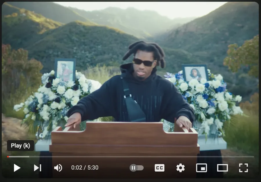 Thumbnail for the official lyrics youTube video showing someone at a podium at a funeral 