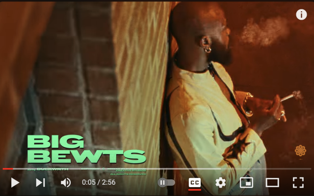 Thumbnail for the youTube video showing Duckwrth smoking smoking while leaning on a brick wall.