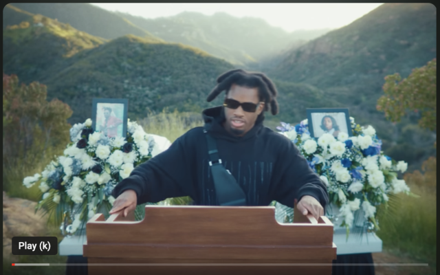 Thumbnail for the official lyrics youTube video showing someone at a podium at a funeral 
