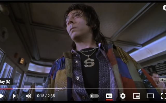 A thumbnail of the youTube video,  Paul Reubens as The Spleen, wearing patchwork clothing and poor complextion with zits